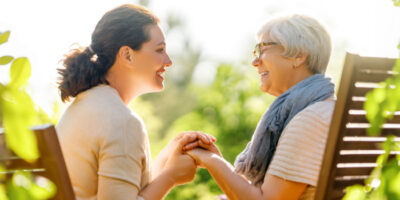 Eine Frau und ihre Mutter sitzen im Garten und genießen ein Gespräch